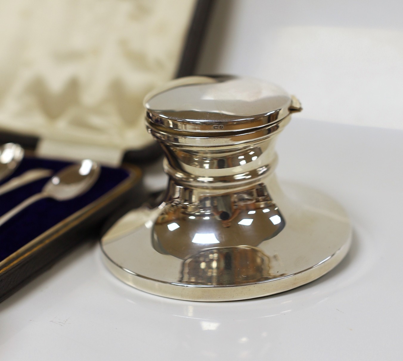 Small silver including a mounted inkwell, tea strainer on stand, mustard pot, small dish and cased set of six coffee spoons with sugar tongs.